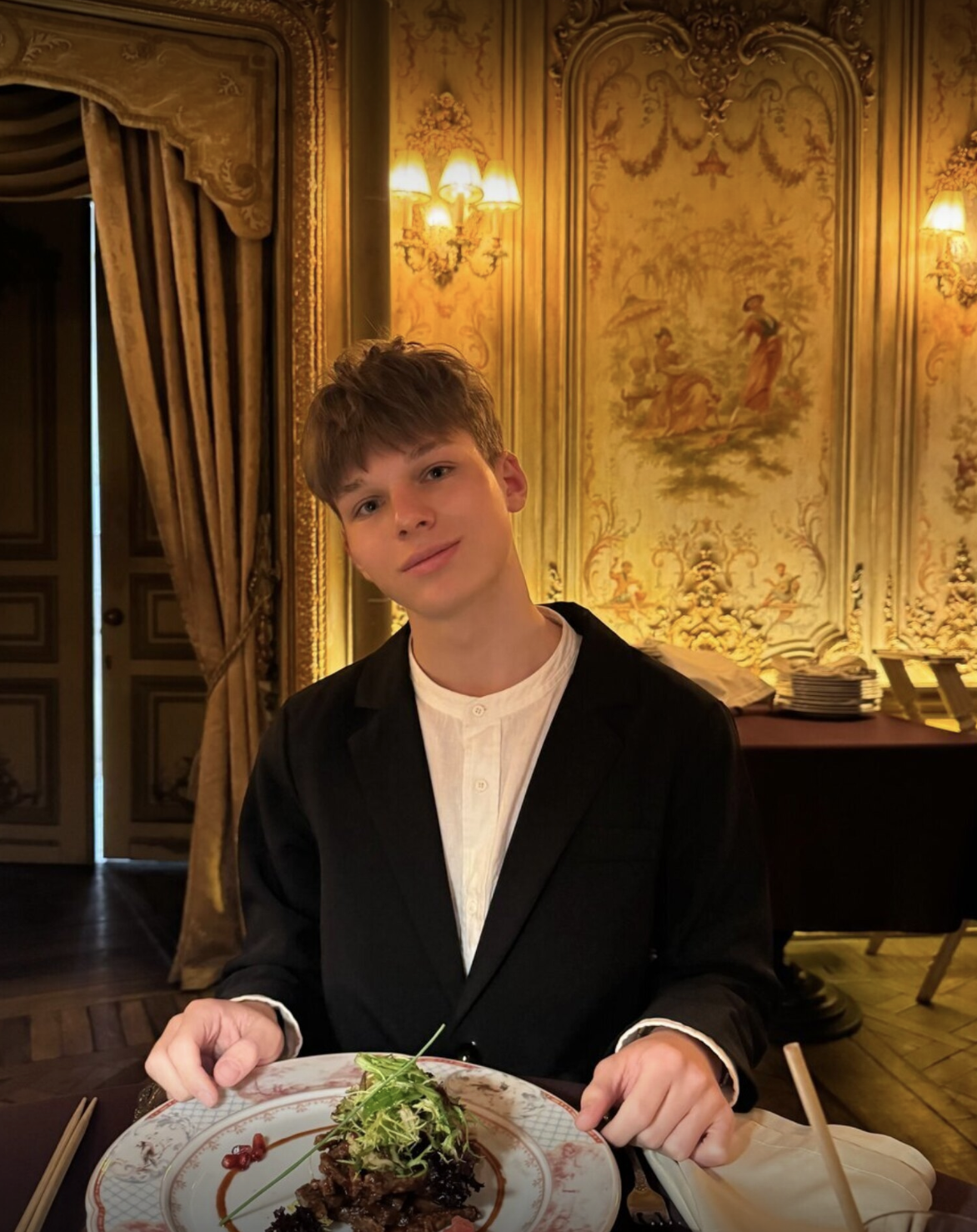 Max Cool wearing a dark jacket, seated at a restaurant table
